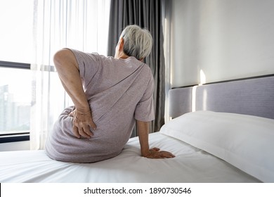 Stressed Asian Senior Woman Suffering From Backache,sitting On Bed Massage Her Waist Pain,unhappy Old Elderly People Waking Up In The Morning After Sleeping On Uncomfortable Mattress Or Bad Posture