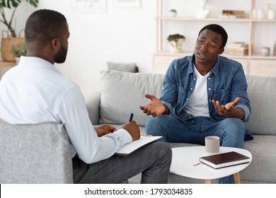 Stressed Black Man Explaining His Problems To Psychologist At Individual Therapy Session At Office, Copy Space