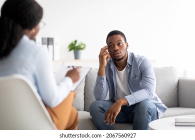 Stressed Black Man Suffering From Depression, Counselor Providing Professional Assistance At Medical Office. Unhappy Male Patient Having Consultation With Psychologist, Receiving Help