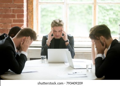 Stressed boss and executive team searching problem solution at meeting, partners holding heads in hands depressed by failure bad news, feeling desperate about company bankruptcy or financial crisis