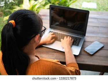 Stressed Business Asian Young Woman Is Working With Laptop On Wooden Table At The Backyard. Working On Weekend Concept.