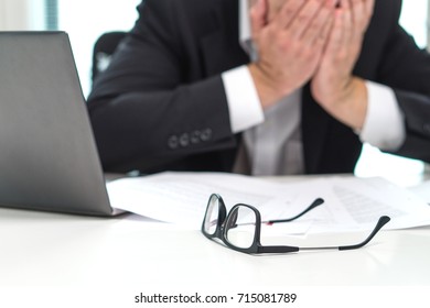 Stressed business man covering face with hands in office. Working over time or too much. Problem with failing business or confusion with crisis. Entrepreneur in bankruptcy. Burnout and overwork.