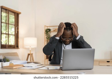 Stressed business man sitting at office workplace. Tired and overworked black man. Young african american exhausted men in stress working on laptop computer. - Powered by Shutterstock