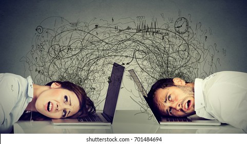 Stressed business woman and man resting head on laptop sitting at table frustrated with each other exchanging with clutter of negative thoughts and emotions. Distant relationship concept - Shutterstock ID 701484694