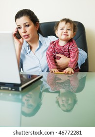 Stressed Business Woman In Office, Holding Her Little Girl While Talking On Mobile Phone. Vertical Shape