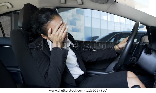 Stressed business woman sitting in car,\
suffering from headache,\
problems