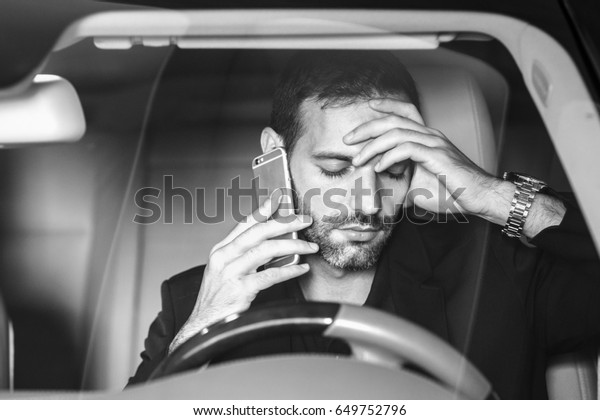 Stressed businessman calling on a mobile phone in\
the car.