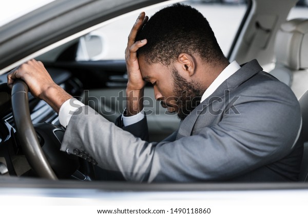 Stressed businessman feeling\
headache in car, stop the car, keeping hand to head and feeling\
anxiety