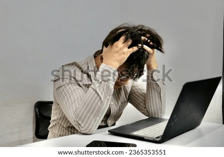 Stressed businessman graving a hair and having problems and headache at work sitting with laptop.