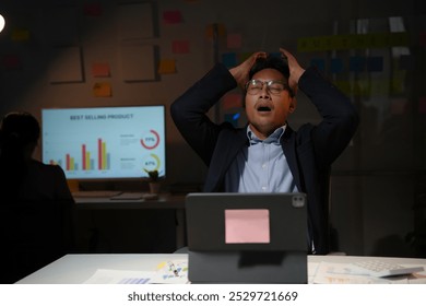 Stressed businessman holding his head with his hands, working late at night in the office - Powered by Shutterstock