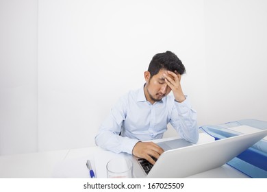 Stressed businessman with laptop sitting at desk in office - Shutterstock ID 167025509