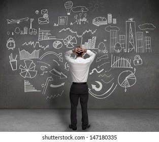 Stressed businessman looking at drawings of charts and sketches on a wall - Powered by Shutterstock