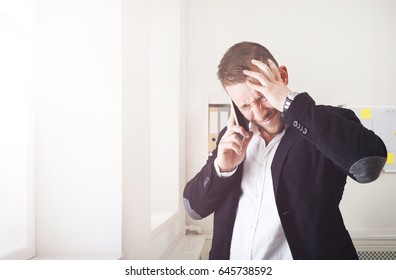 Stressed Businessman Shout Making Call With Mobile Phone Near Window In Modern Office. Annoyed, Frustrated Man Has Unpleasant Conversation, Show Negative Emotion. Place For Copy Space