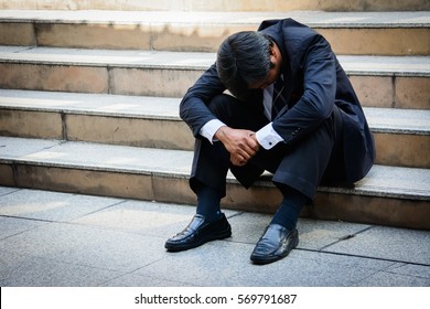 Stressed businessman sitting at stairway outdoor.Bankrupt businessman sitting outdoor. - Powered by Shutterstock