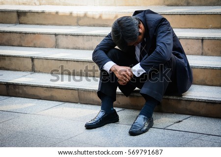 Stressed businessman sitting at stairway outdoor.Bankrupt businessman sitting outdoor.