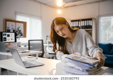 Stressed businesswoman overwhelmed by paperwork in office, struggling to meet deadline. Balancing career challenges in corporate world - Powered by Shutterstock