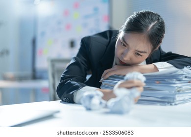 Stressed businesswoman overwhelmed by work in office, holding crumpled paper, looking tired and frustrated - Powered by Shutterstock