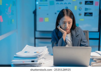 Stressed businesswoman working late in dimly lit office, typing furiously on laptop surrounded by paperwork, reflecting intensity and exhaustion. Captures reality of burnout in corporate world - Powered by Shutterstock