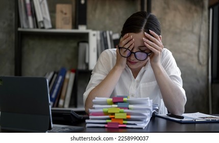 Stressed businesswoman working at office on document and laptop looking worried, tired and overwhelmed. - Shutterstock ID 2258990037