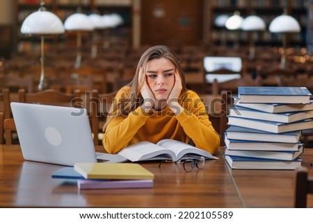 Stressed college student tired of hard learning with books and laptop in exams tests preparation, overwhelmed high school teen girl exhausted with difficult studies or too much homework.