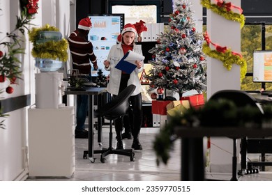 Stressed corporate coworkers working in busy festive decorated office during winter holiday season. Employees solving various project tasks with deadline approaching soon in Christmas adorn workspace - Powered by Shutterstock