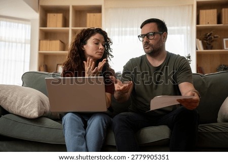 Stressed couple looking worried while managing household finance bills and debts at home