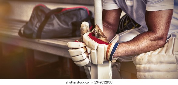 Stressed cricket player sitting on bench at locker room, Close-up