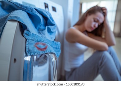 Stressed crying woman found on the collar of her husband's shirt female red lipstick marks while laundry. Male cheating and break up, relationship problems. Break in relationship