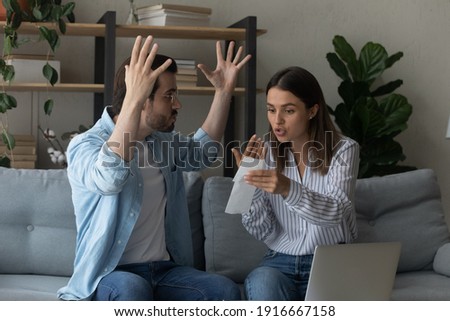 Stressed emotional couple arguing fighting when checking financial papers together finding unexpected debt lack of money on bank account. Mad angry husband scolding wife for overspending family budget