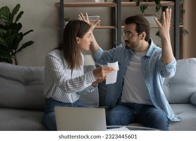 Stressed emotional young family couple arguing, blaming each other of overspending money, having financial problems, made mistakes in bills taxes payments, feeling depressed together at home. - Powered by Shutterstock