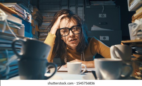 Stressed exhausted woman sitting at office desk and working overtime, she is overloaded with work - Powered by Shutterstock