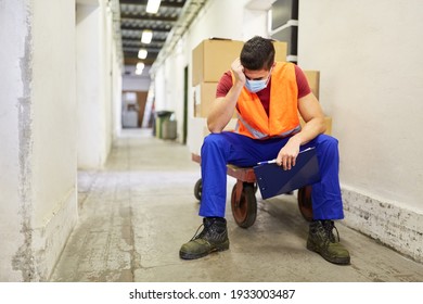 Stressed And Exhausted Worker With Face Mask Because Of Covid-19 In The Warehouse