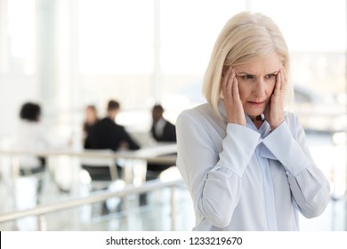 Stressed Fatigued Mature Businesswoman Touching Temples Suffer From Headache Migraine At Office Meeting, Tired Exhausted Old Woman Employee Feels Dizzy At Work, Climax And Hormone Imbalance Concept