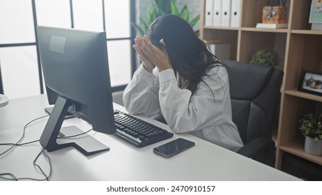 Stressed female doctor in hospital office covers face with hands, showcasing burnout and fatigue at workplace. - Powered by Shutterstock