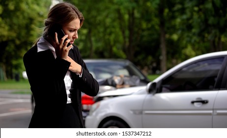 Stressed female driver talking phone car collision scene, auto damage, insurance