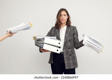 Stressed female worker and business woman holding a pile of paperwork while getting more work to do. Looking frustrated in camera, isolated on white background. Concept: Too much work - Shutterstock ID 2140866997