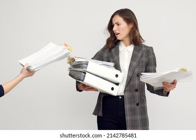 Stressed Female Worker And Business Woman Holding A Pile Of Paperwork While Getting More Work To Do. Looking Frustrated With Too Much Work, Isolated On White Background. Concept: Too Much Work