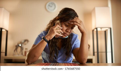 Stressed Filipina Nurse Taking Phonecall At Home