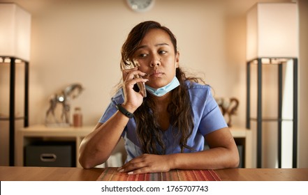 Stressed Filipina Nurse Taking Phonecall At Home