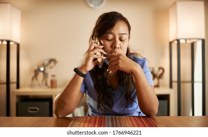 Stressed Filipina Nurse Taking Phonecall At Home