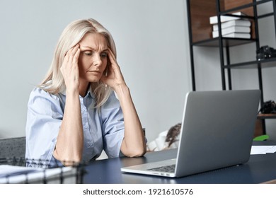 Stressed Forgetful Old Middle Aged Business Woman Suffering From Headache After Computer Work. Tired Upset 50s Lady Massaging Head Feeling Stress, Fatigue Or Migraine Using Laptop At Home Office.