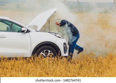 Stressed And Frustrated Driver Pulling His Hair While Standing On The Road Next To Broken Car. Road Trip Problems And Assistance Concepts. Smoke.