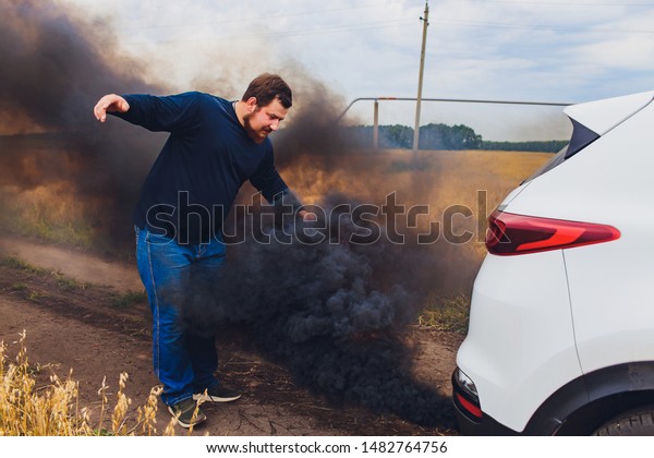 Stressed and frustrated driver pulling his hair
while standing on the road next to broken car. Road trip problems
and assistance concepts.
smoke.