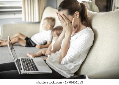 Stressed Frustrated Mother At Home With Children Working On Computer. 