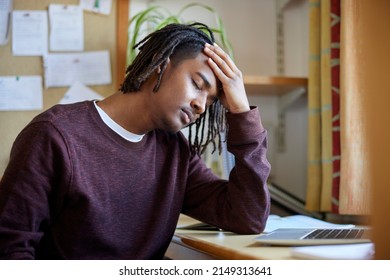 Stressed Male University Or College Student With Poor Mental Health Studying With Laptop At Desk In Room