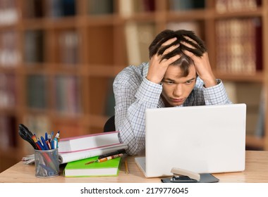 Stressed Male University Or College Student With Poor Mental Health Studying With Laptop In Room