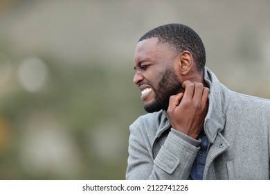 Stressed Man With Black Skin Scratching Itchy Neck In Winter In A Park