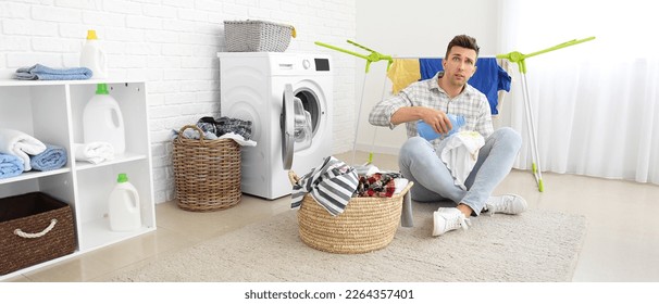 Stressed man doing laundry in bathroom - Shutterstock ID 2264357401