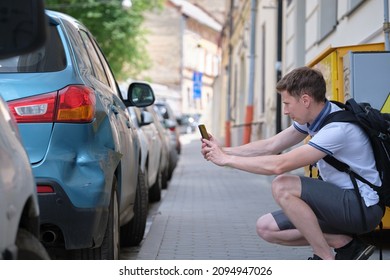 Stressed Man Driver Taking Photo On Mobile Phone Camera Of Dented Fender On Street Side For Emergency Service After Car Accident. Road Safety And Insurance Concept