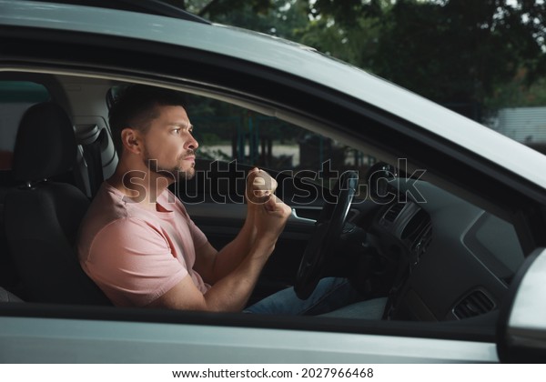 Stressed man in\
driver\'s seat of modern\
car